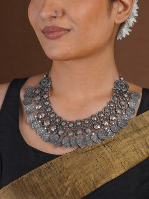 Close angled view of Sitavan oxidized collar necklace with floral mesh embossed coin motifs and engraved heart drops