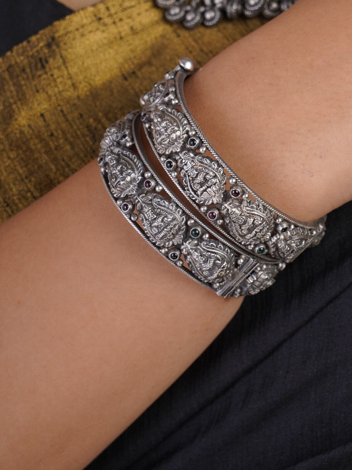 Sitavan Lakshmi temple oxidised silver bangle pair with deity relief motifs and coloured stone accents by Sita Jewellery