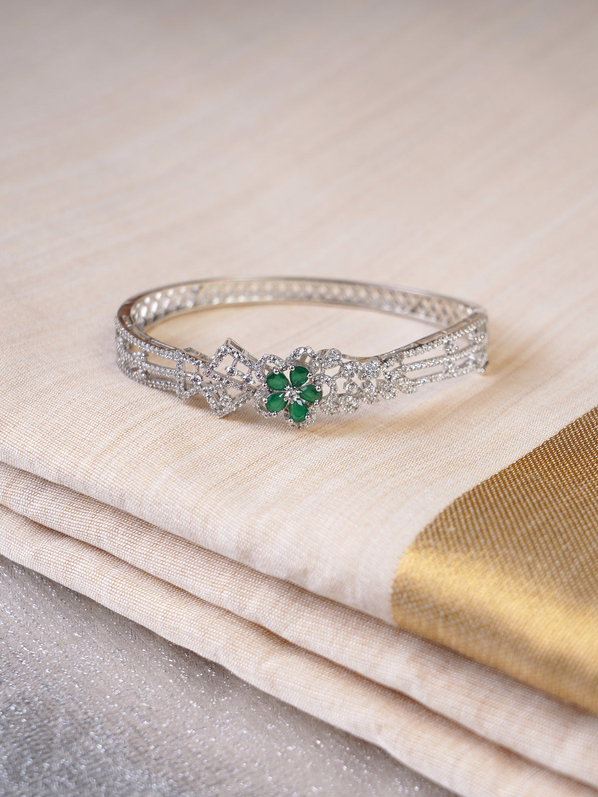 Sitamani Emerald floral AD silver bracelet worn on the wrist with a cream and gold saree by Sita Jewellery