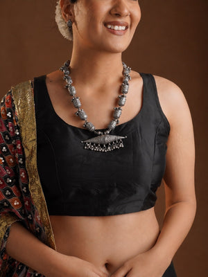 Full view of Sitavan oxidized tribal necklace with carved bead strand horizontal pendant and small metal drop fringe