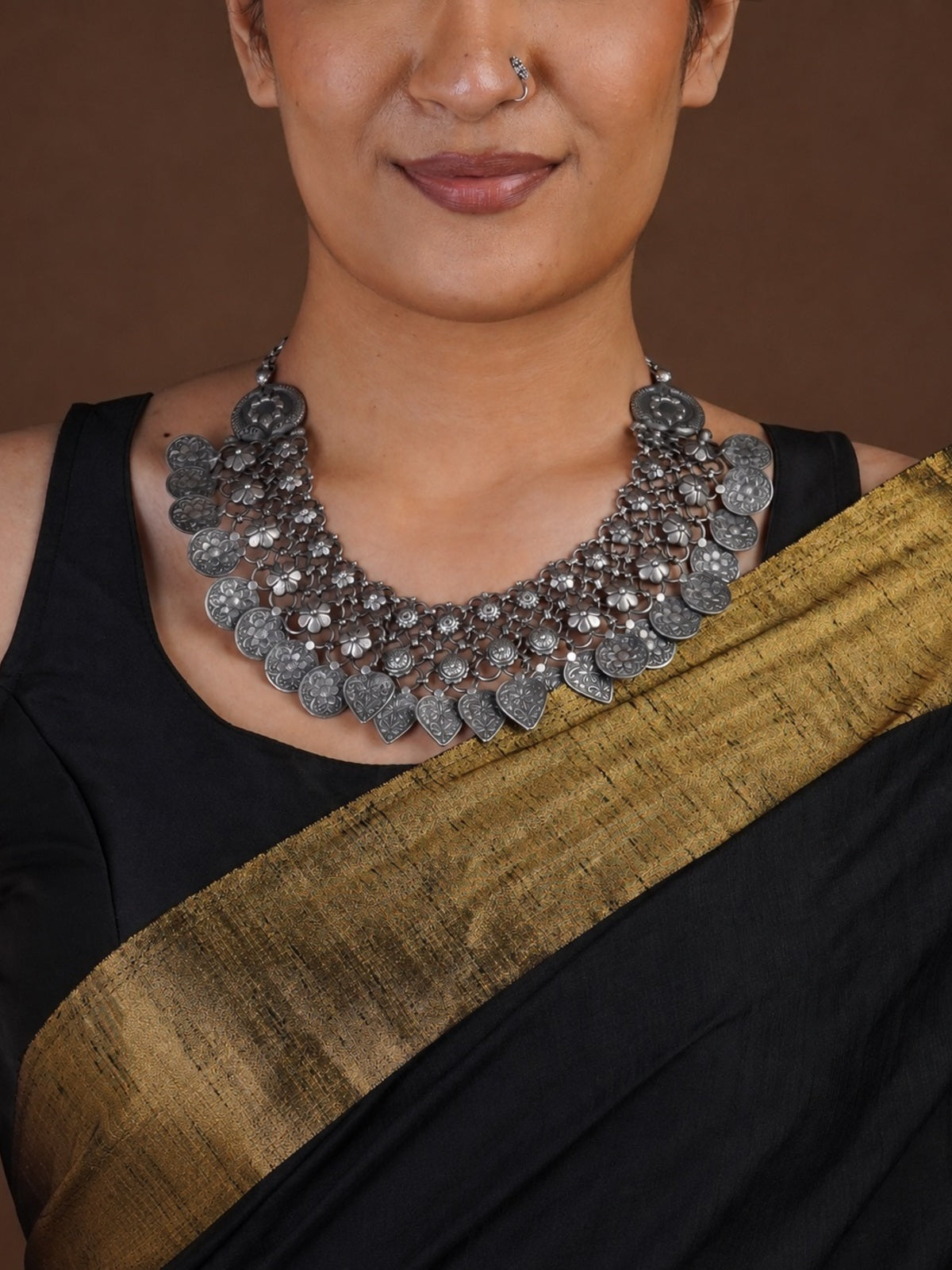 Sitavan floral coin heart fringe oxidized collar necklace styled with black saree and matching silver-tone jhumkas