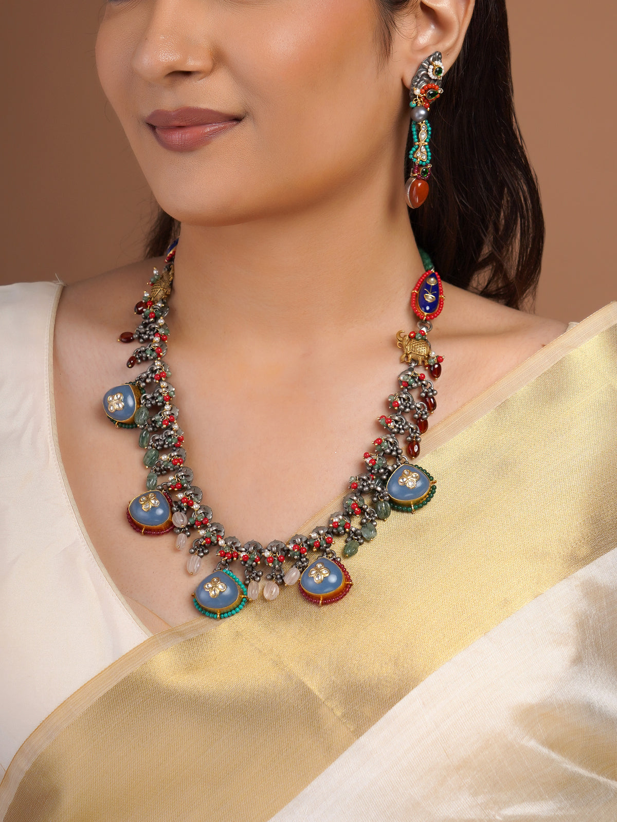 Sitamohur matching fusion earring close-up with oxidized silver-tone base, green red turquoise beads and orange teardrop stone