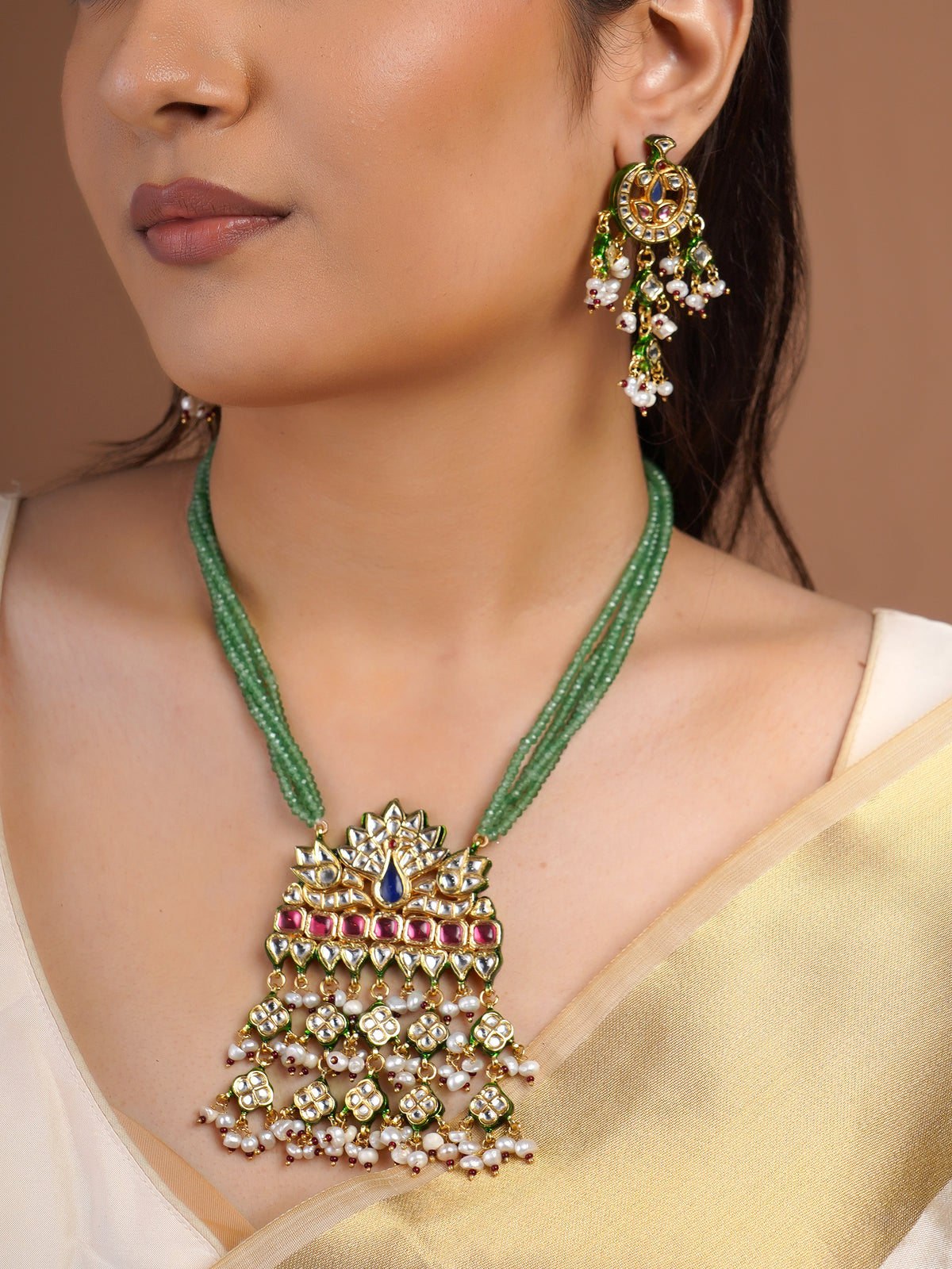 Samragni matching peacock kundan statement earring close-up with green enamel-style details, blue ruby stones and pearl cluster drops