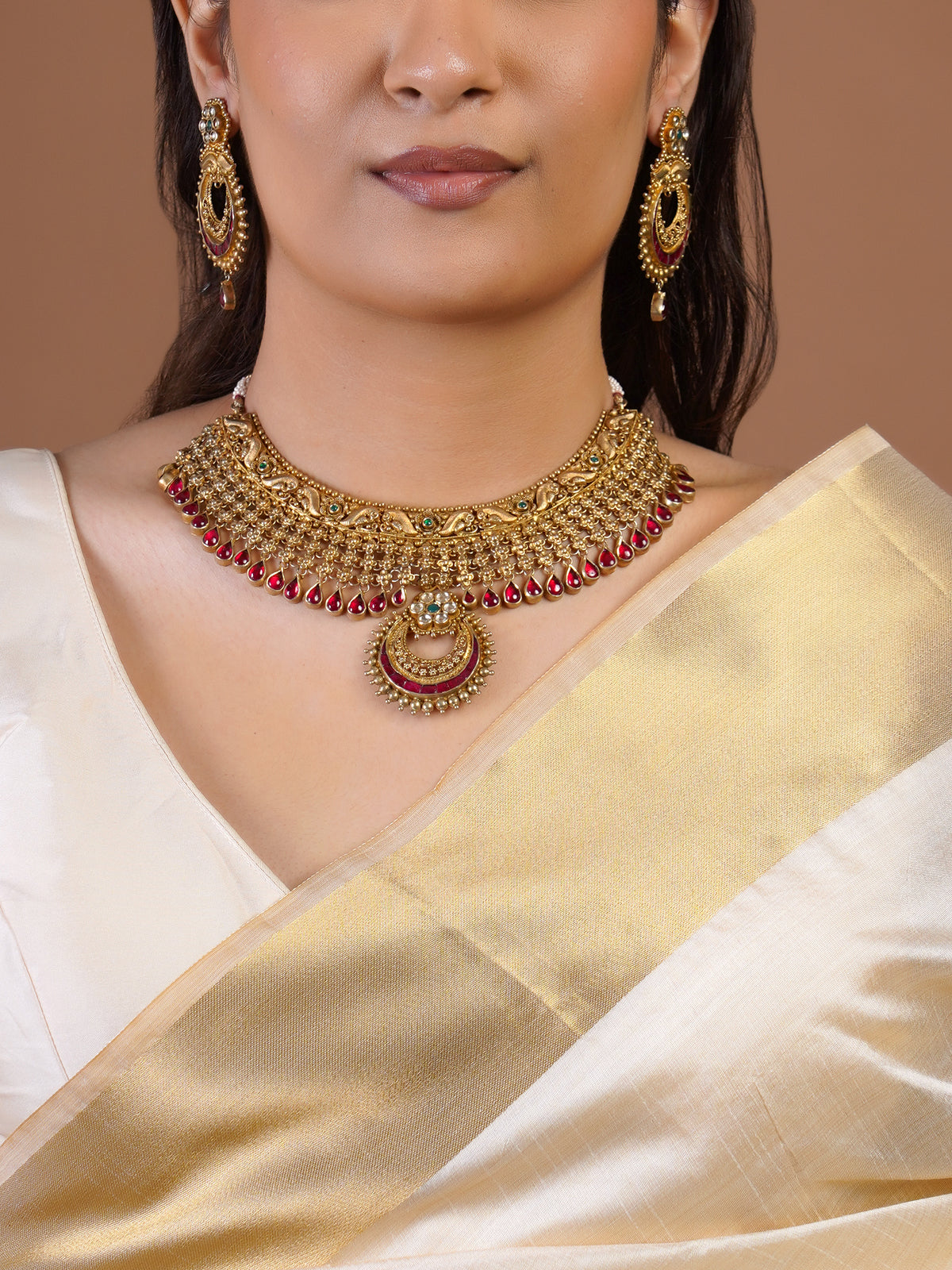 Samragni antique gold statement earring close-up with green floral stud, ruby crescent details and single ruby drop