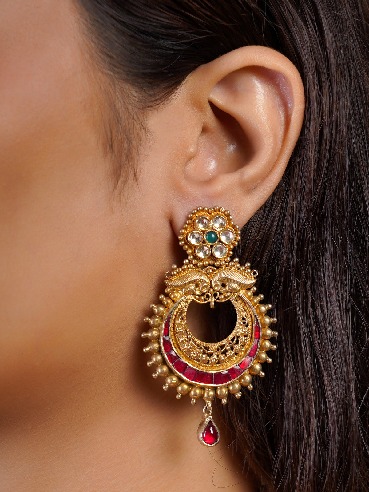 Samraagni antique gold statement earring close-up with green floral stud, ruby crescent details and single ruby drop