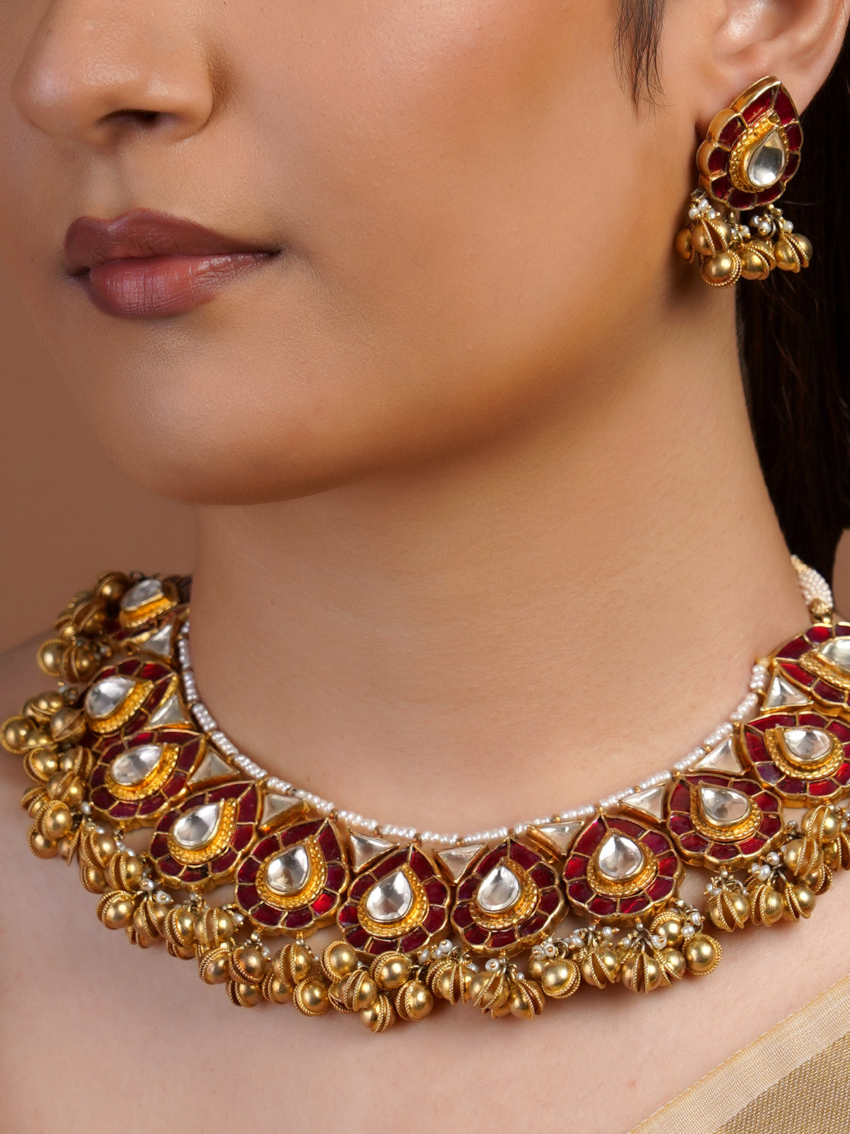 Samragni ruby kundan teardrop earring close-up with white centre stone, antique gold frame and gold bead fringe