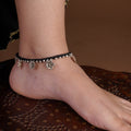 Sitavan black thread oxidized silver anklet with small floral charms and antique metal accents worn on the ankle