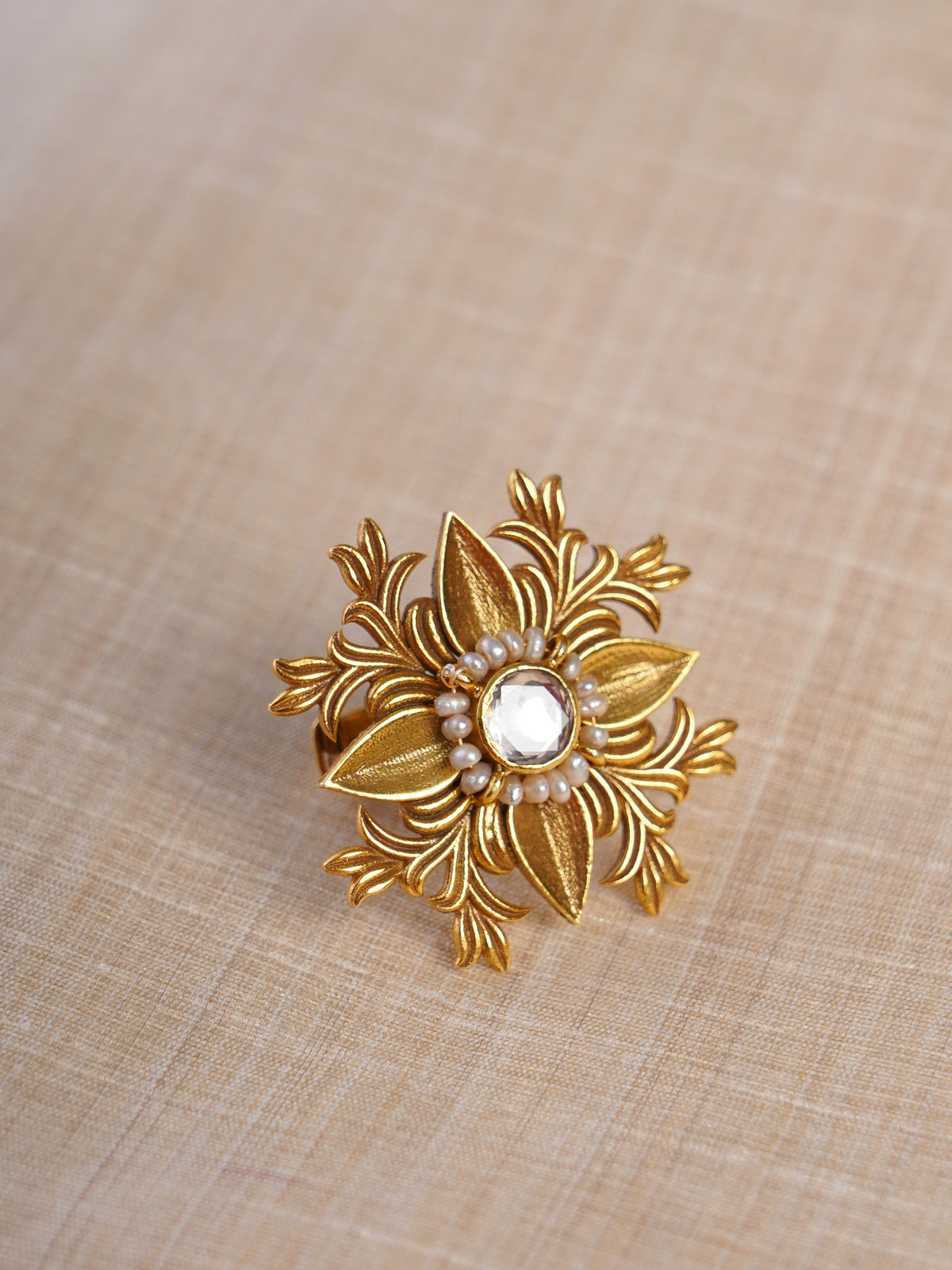 Sitaratna floral pearl halo moissanite statement ring shown on hand with sculpted gold-tone leaf design